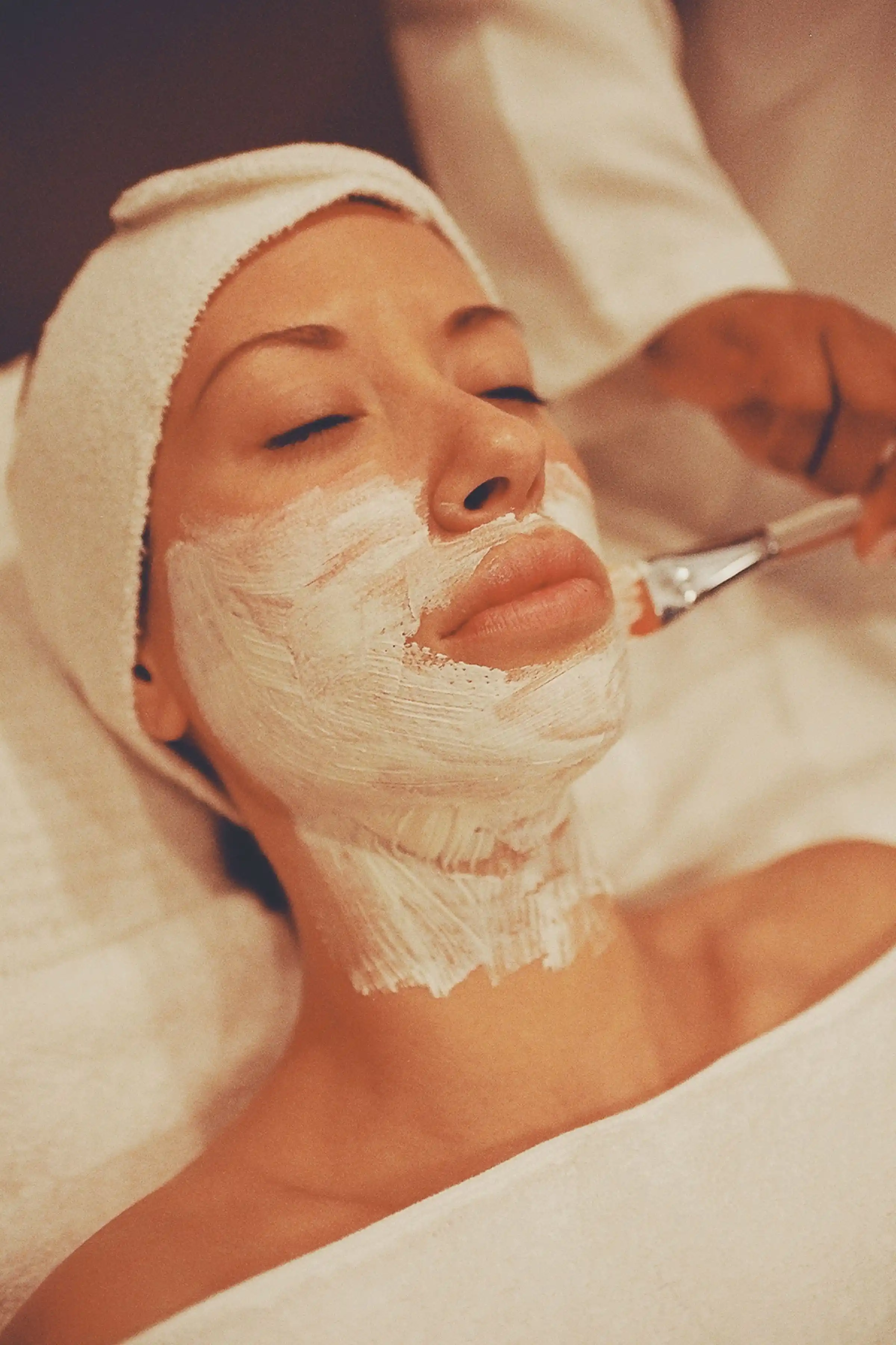 Beautician applying a facial mask during a home facial appointment in Jaipur